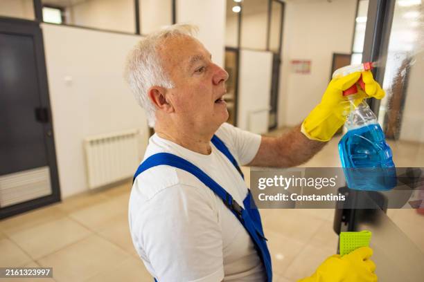 senior caucasian male janitor, cleaning the classroom glass at the school building - caretaker stock pictures, royalty-free photos & images