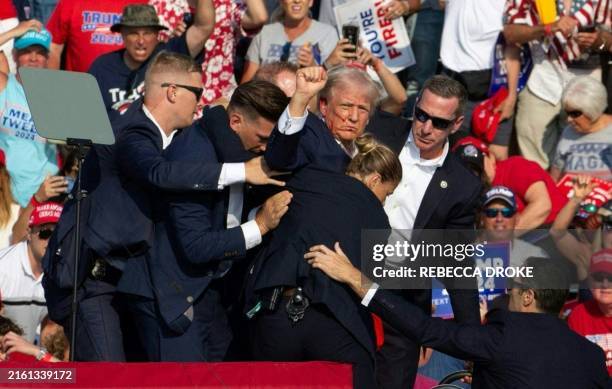 Republican candidate Donald Trump is seen with blood on his face surrounded by secret service agents as he is taken off the stage at a campaign event...
