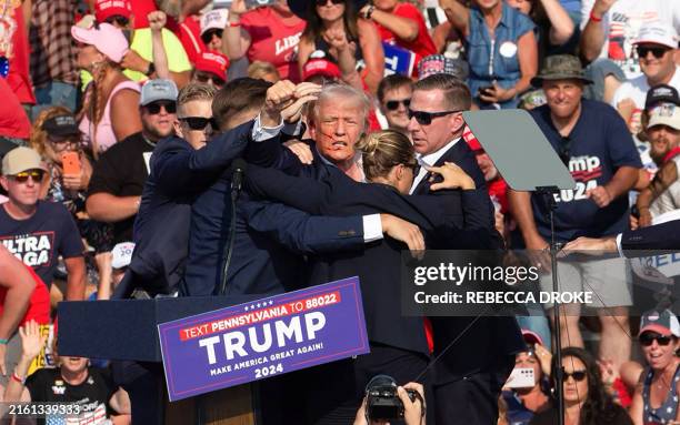 Republican candidate Donald Trump is seen with what appears to be blood on his face surrounded by secret service agents as he is taken off the stage...