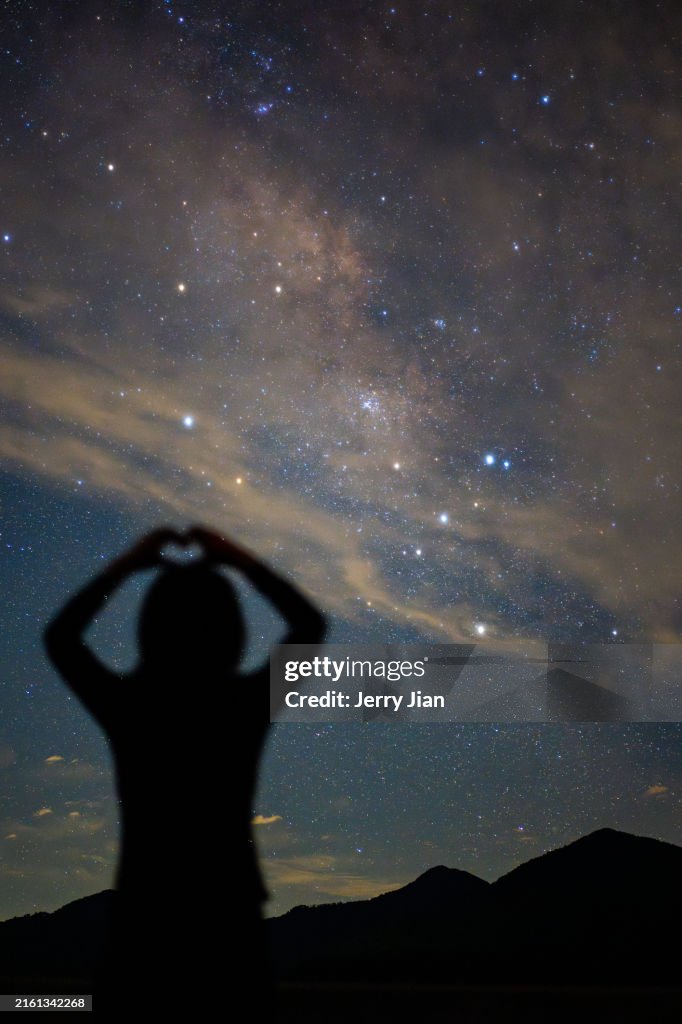 A girl standing below the galaxy