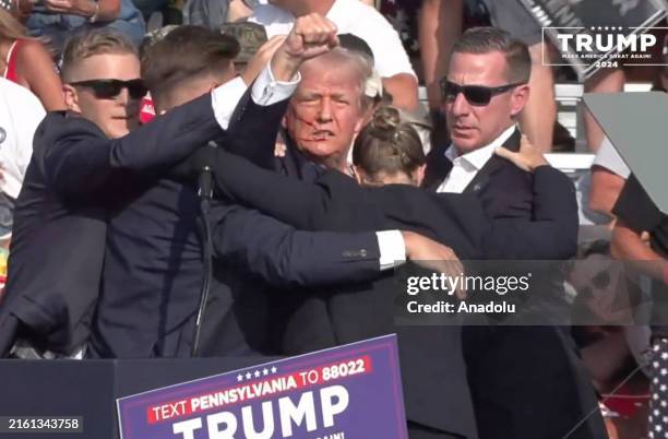 Screen grab captured from a video shows Republican presidential candidate former President Donald Trump appears to be injured after gunshots were...