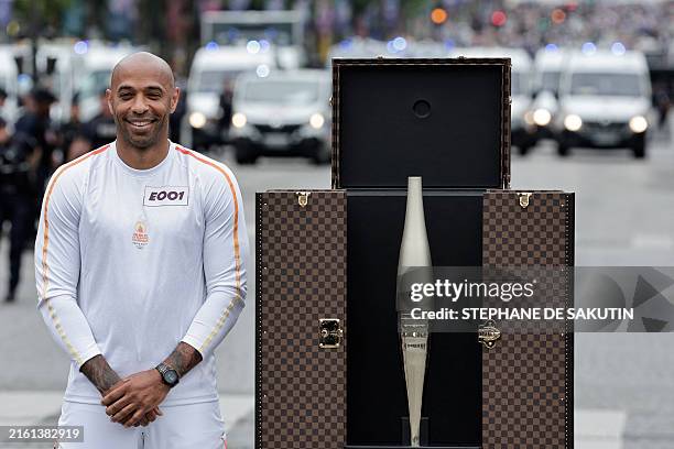 French football Olympics 2024 coach Thierry Henry poses next to a trunk containing the Olympic torch, custom-designed and manufactured by Louis...