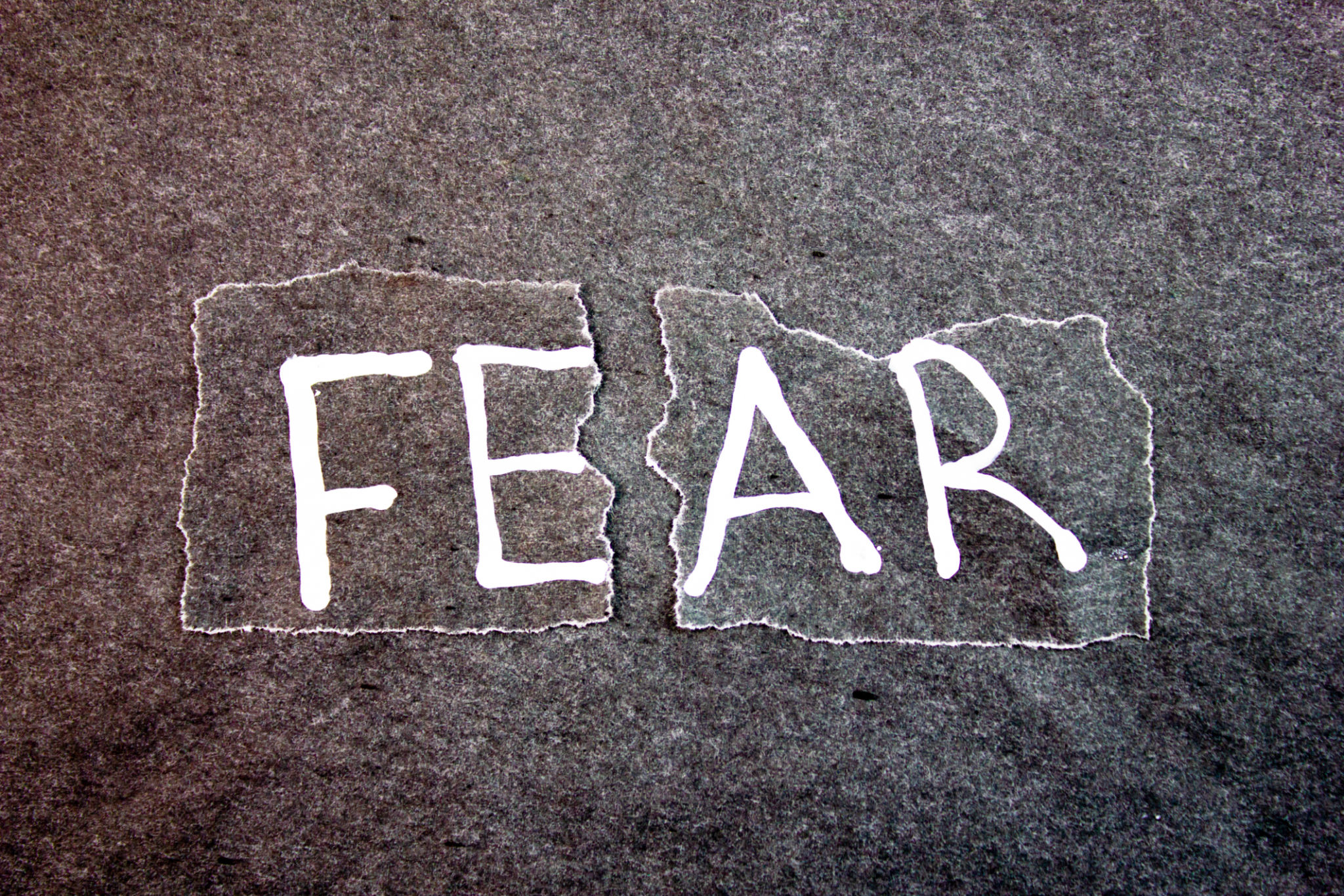 FEAR, the text is written on torn paper. Fear white text on black background,concept. Overcoming fear. FEAR, the text is written on torn paper. Fear white text on black background,concept. Overcoming fear.