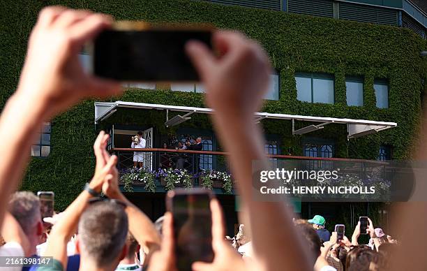 Spain's Carlos Alcaraz celebrates with the winner's trophy as he shows it to the crowd from the Centre Court balcony after winning against Serbia's...