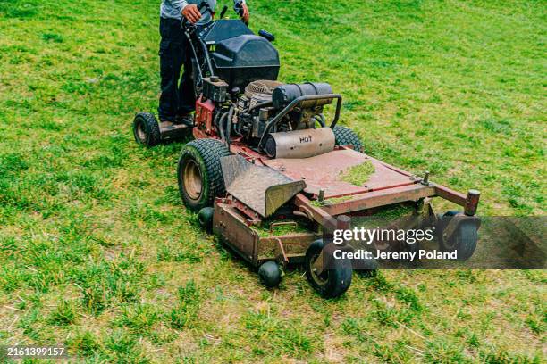 elevated view of a man using a stand-on lawnmower, caring for a park with a landscaping company - gräsklippare bildbanksfoton och bilder