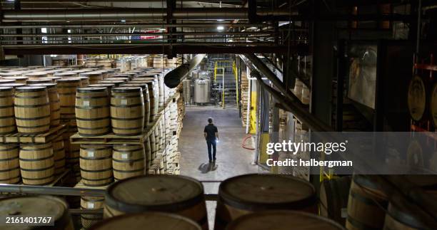 high angle view of distillery owner in warehouse full of barrels - barrel stock pictures, royalty-free photos & images