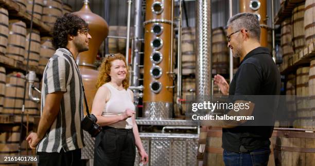 side view of hispanic distillery owner with two international tourists - whiskey proeven stockfoto's en -beelden