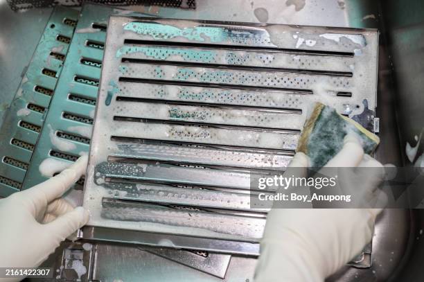 someone using a scrub sponge to cleaning a dirty cooker hood filters at the sink. - clean oven stock pictures, royalty-free photos & images