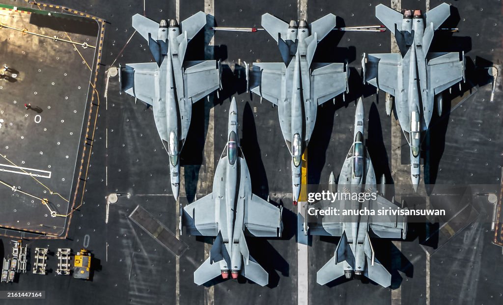 F/A-18E Super Hornet is parked on an American military aircraft carrier at sea.