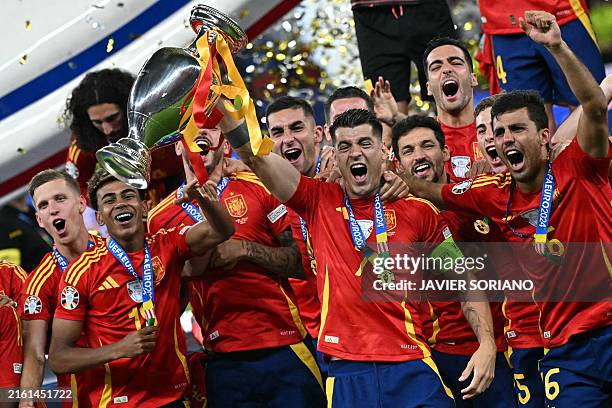 Spain's forward Alvaro Morata rises the trophy next to Spain's midfielder Rodri and Spain's forward Lamine Yamal after winning the UEFA Euro 2024...