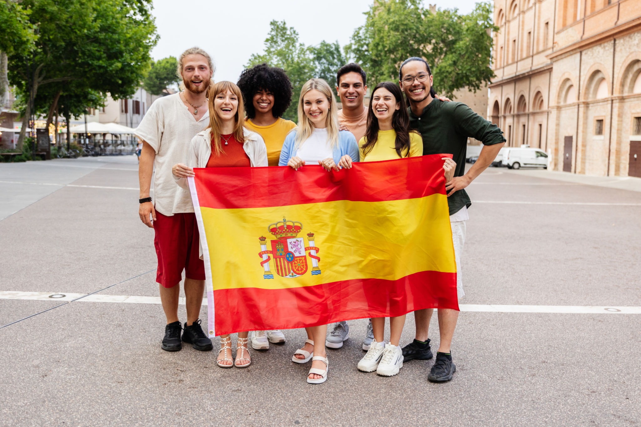 Diverse group of people looking at the camera holding spanish flag outdoors Diverse group of people looking at the camera holding spanish flag outdoors