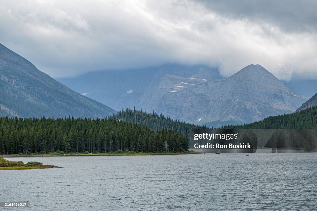 Mountains obscured by clouds along Swift current Lake at Many Glacier Hotel in Glacier National Park, Montana