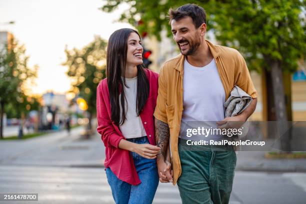 couple walking hand in hand on an urban street happily - couple crossing street stock pictures, royalty-free photos & images