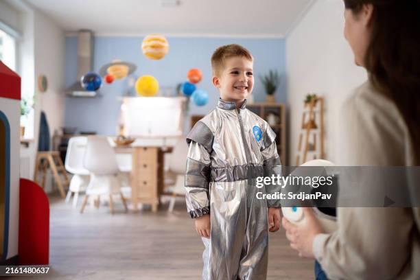 boy in a space suit playing with his mom at home, imagining space travel. - roupa de astronauta imagens e fotografias de stock