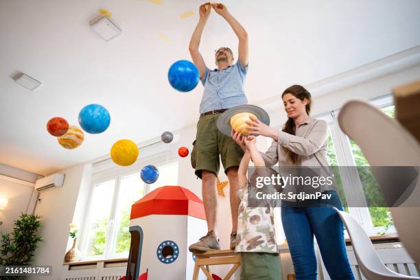 family decorating their home with a model of a solar system - star mothers stock pictures, royalty-free photos & images