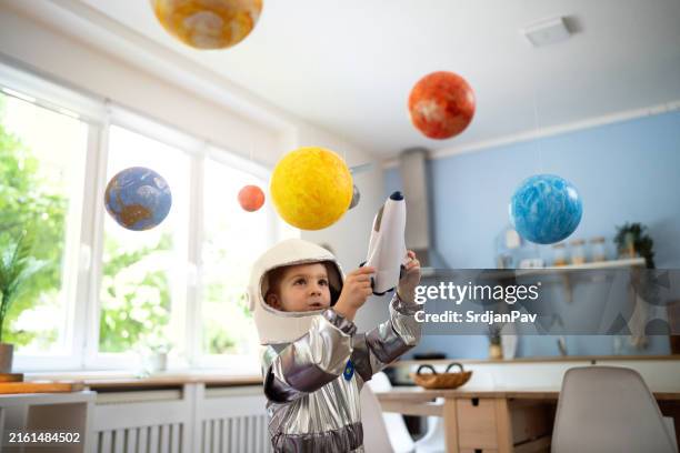 niño con un traje espacial jugando en casa, imaginando viajes espaciales. - disfraz fotografías e imágenes de stock