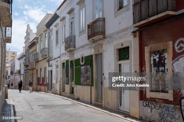 People walk along Rua de Sao Pedro past a mix of houses and apartments on June 27, 2024 in Faro, Portugal.