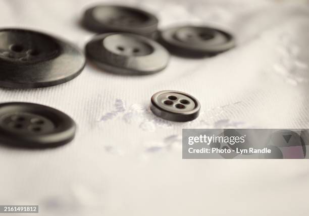 lyn randle black buttons spread on white embroidered fabric - sewing stock pictures, royalty-free photos & images