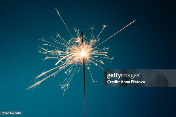 burning sparkler with many beautiful sparks on blue background. concept of new year or birthday celebration. copy space for your design - candela magica foto e immagini stock