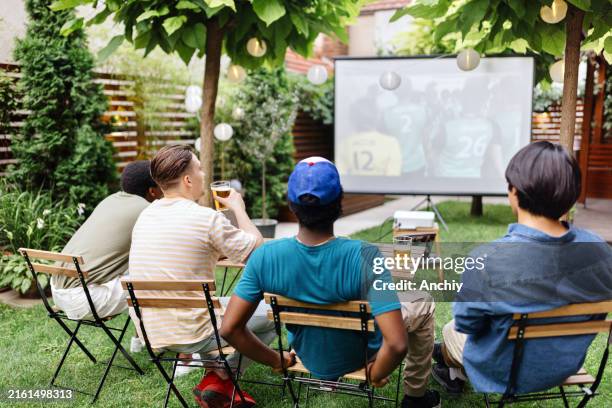 group of friends having fun while watching sports in the backyard - projection equipment stock pictures, royalty-free photos & images