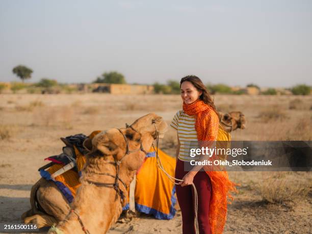 woman petting camel in the desert at sunset - jaisalmer stock pictures, royalty-free photos & images