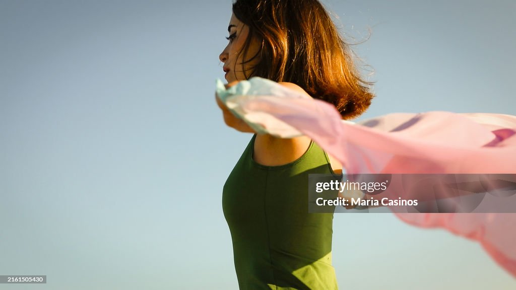 Giovane donna che tiene il velo colorato che ondeggia sul vento