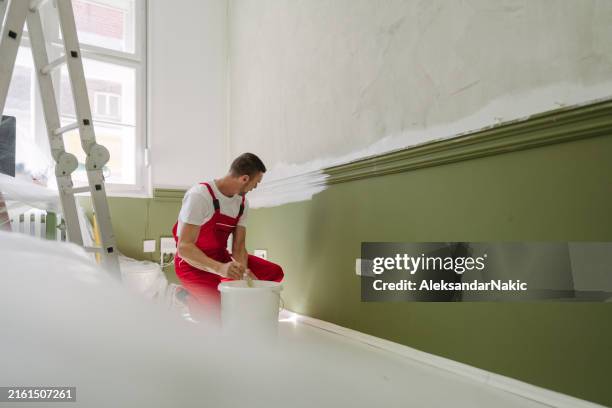 a professional house painter's painting an apartment - a man goes through the wall stock pictures, royalty-free photos & images
