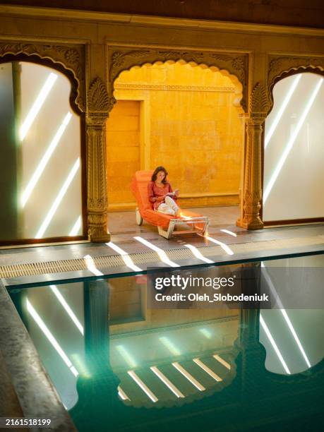 woman reading book sitting on chair in haveli during trip - jaipur stock pictures, royalty-free photos & images