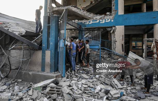 Palestinians and UN workers examine the destroyed makeshift tents and shelters after Israeli attack hits a United Nations Relief and Works Agency for...