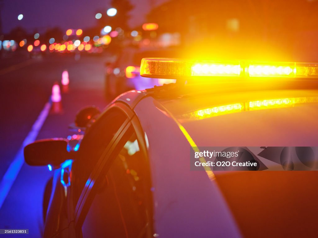 Voiture de police arrêtée sur une route la nuit avec des feux d’urgence