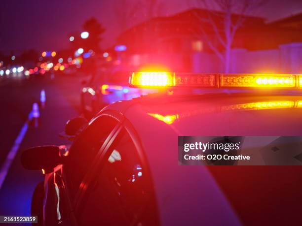 police car stopped on a road at night with emergency lights - police photos et images de collection