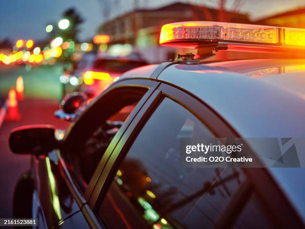 coche de policía detenido en una carretera por la noche con luces de emergencia - luz-de-vehículo-de-policía fotografías e imágenes de stock