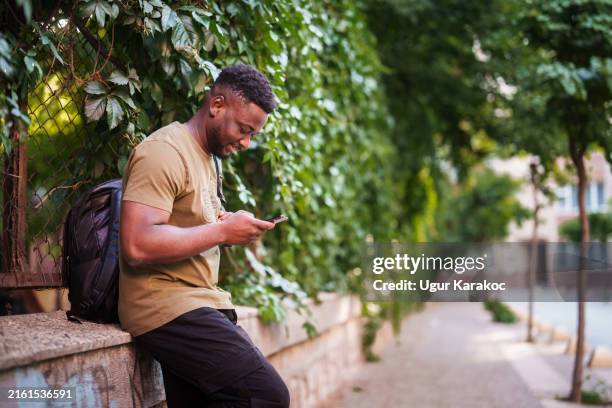 togolesischer mann benutzt handy auf der straße der stadt. - westafrikanische kultur stock-fotos und bilder