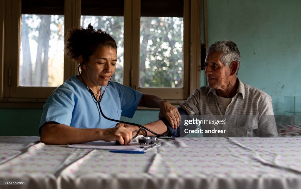 Médico rural visitando a un paciente en su domicilio y tomándole la presión arterial