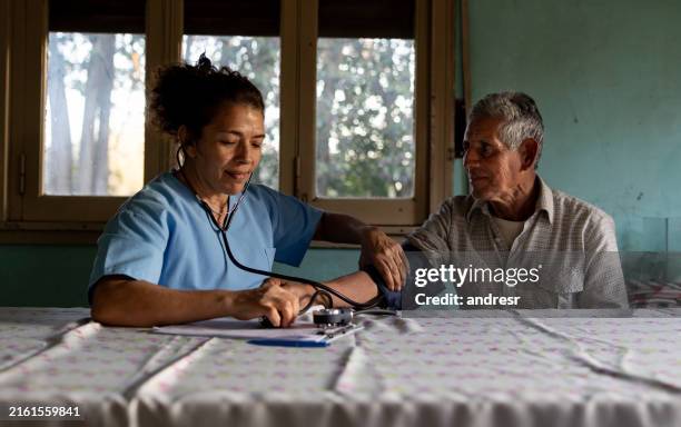 médico rural visitando a un paciente en su domicilio y tomándole la presión arterial - países en vías de desarrollo fotografías e imágenes de stock