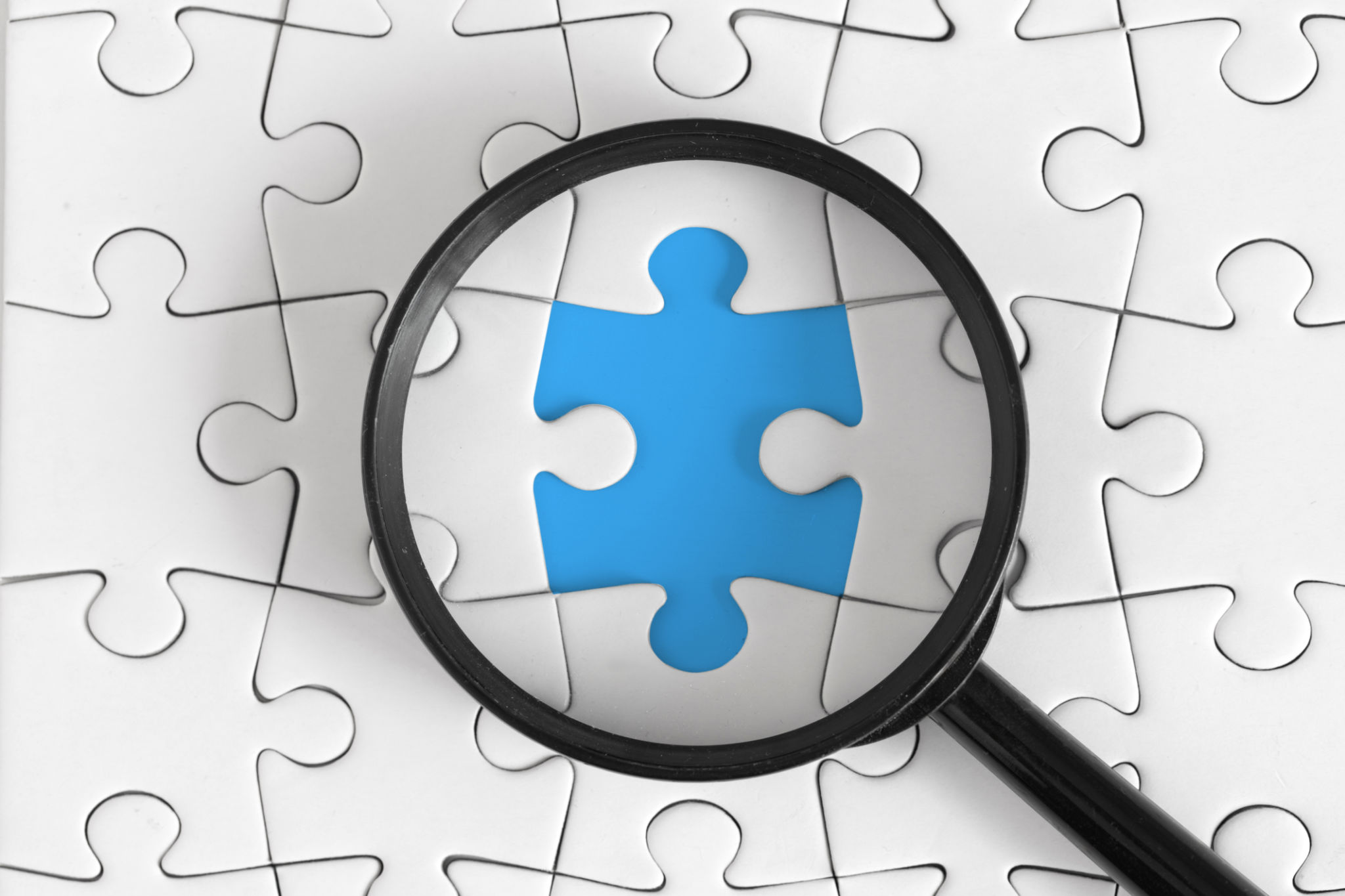 Magnifying Glass Highlights Missing Puzzle Piece on Blue Background Magnifying Glass Highlights Missing Puzzle Piece on Blue Background