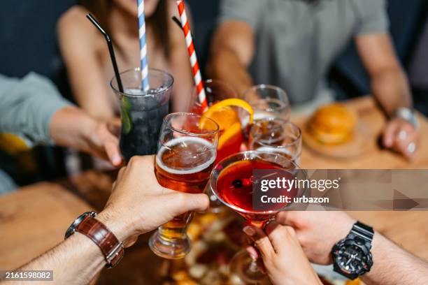 gruppo di amici che fanno il tifo con cocktail e birra in un bar al chiuso - happy hour foto e immagini stock