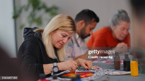 group of multi-racial people with different ages joining art painting therapy session class - artist table stock pictures, royalty-free photos & images
