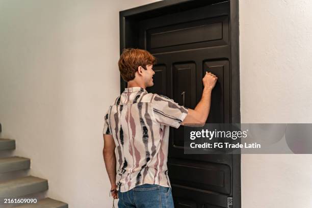 giovane che bussa alla porta - bussare foto e immagini stock