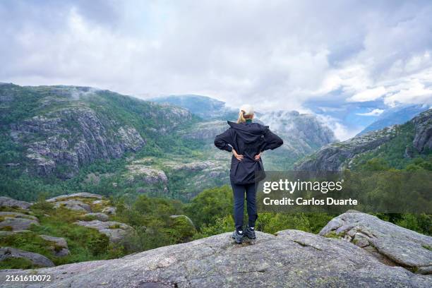 donna bionda caucasica che fa un'escursione in montagna in un fiordo turistico in norvegia - bergen foto e immagini stock