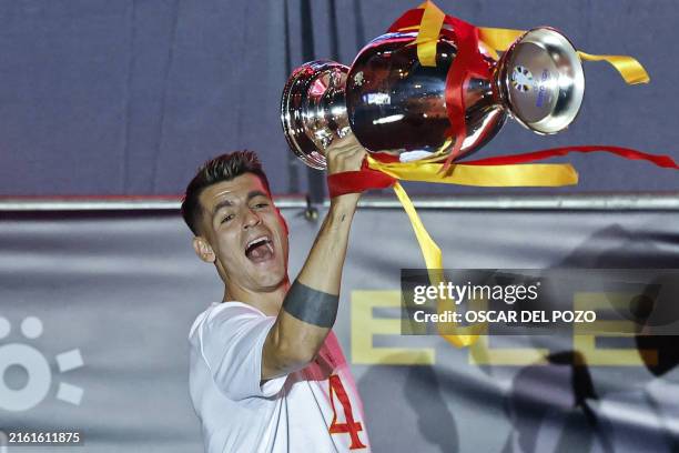 Spain's forward Alvaro Morata celebrates with the trophee as Spanish national football team players celebrate on the stage with fans at Cibeles...