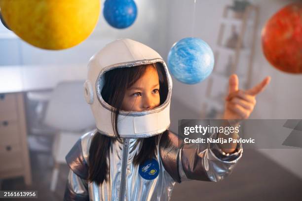 girl in a space suit playing at home, exploring and learning about planets, imagining space travel. - roupa de astronauta imagens e fotografias de stock