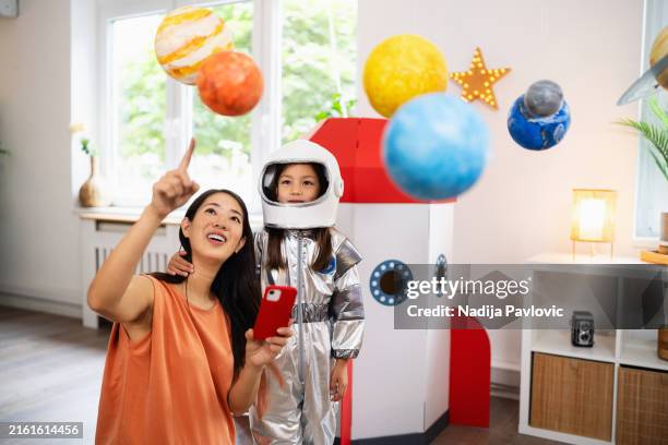madre e hija aprendiendo sobre el espacio a través de un teléfono móvil - cosmonauta fotografías e imágenes de stock