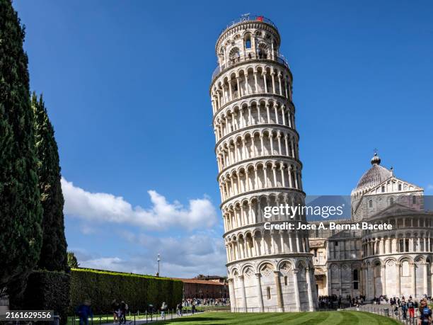 leaning tower and in the background the cathedral in piazza dei miracoli in pisa, italy. - leaning tower of pisa stock pictures, royalty-free photos & images