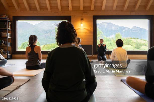 teachers explain yoga technique to diverse group - retreating stock pictures, royalty-free photos & images