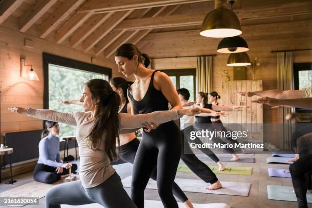 teachers explain yoga technique to diverse group - yogalehrer stock-fotos und bilder