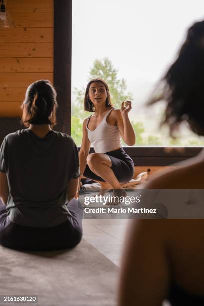 teacher explains yoga technique to diverse group - retreating stock pictures, royalty-free photos & images