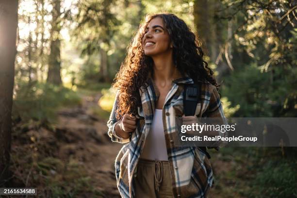 Mujer Alegre Que Camina Por El Sendero Del Bosque Con Mochila, Foto de stock