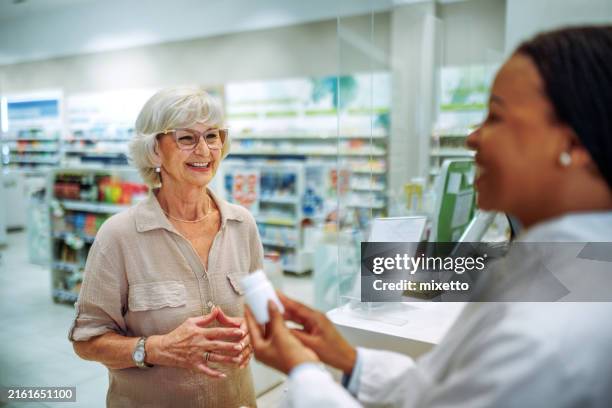 seniorin berät sich mit apothekerin über medikamente in der drogerie - apotheke stock-fotos und bilder