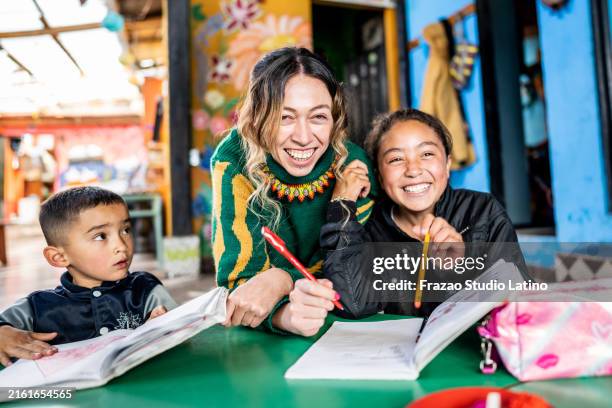 teacher assisting students in the classroom at a children's foundation - orphan stock pictures, royalty-free photos & images